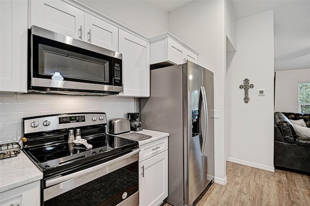 kitchen featuring backsplash, appliances with stainless steel finishes, light hardwood / wood-style flooring, and white cabinets