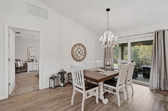 dining room featuring lofted ceiling, light wood-type flooring, and a notable chandelier