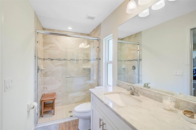 bathroom with an enclosed shower, vanity, hardwood / wood-style floors, and toilet