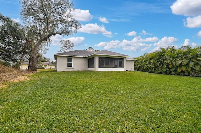 back of property featuring a sunroom and a lawn