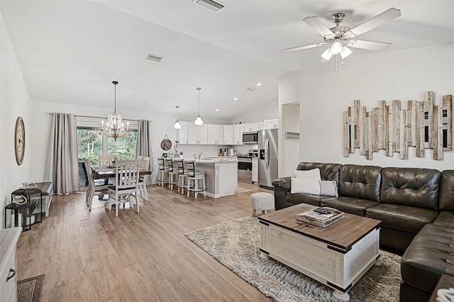 living room featuring lofted ceiling, ceiling fan with notable chandelier, and light hardwood / wood-style flooring