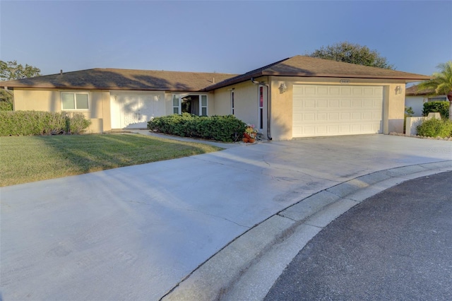 single story home featuring a garage and a lawn