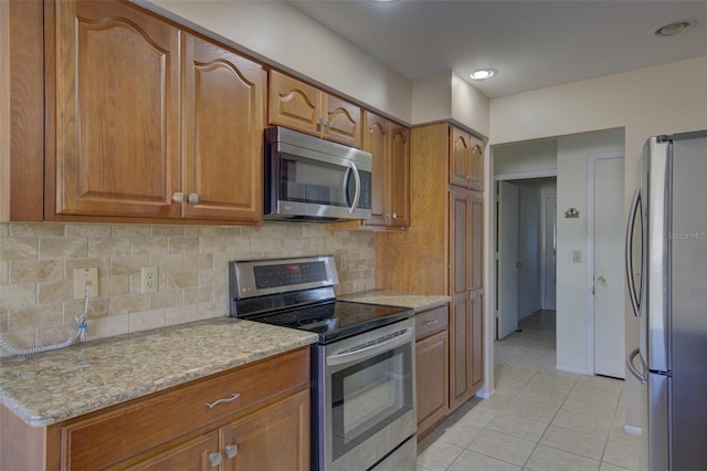 kitchen featuring light tile patterned floors, backsplash, light stone countertops, and appliances with stainless steel finishes