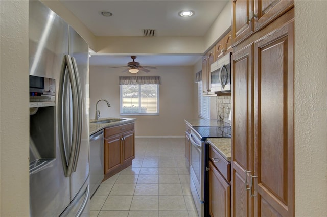 kitchen with sink, light tile patterned floors, ceiling fan, stainless steel appliances, and light stone countertops