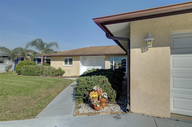 view of side of property featuring a garage and a lawn