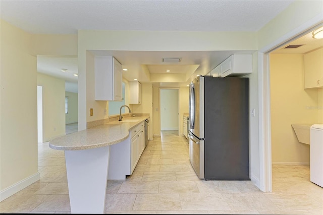 kitchen featuring appliances with stainless steel finishes, white cabinets, light tile patterned flooring, washer / clothes dryer, and kitchen peninsula