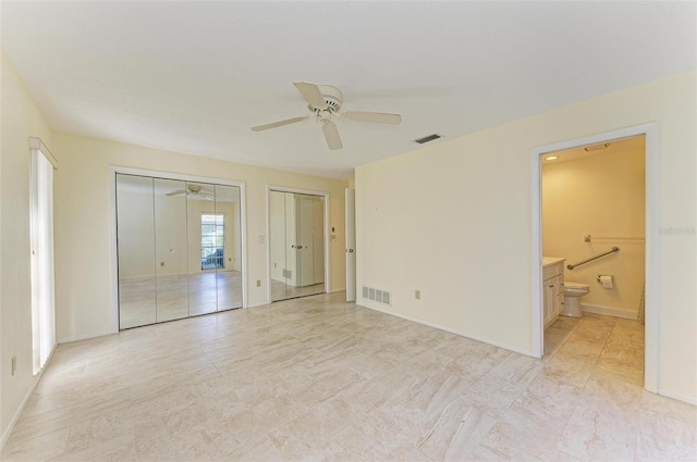 unfurnished bedroom featuring connected bathroom, multiple closets, and ceiling fan