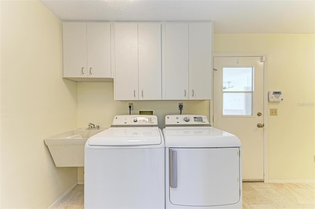 clothes washing area featuring cabinets, washing machine and dryer, sink, and a textured ceiling