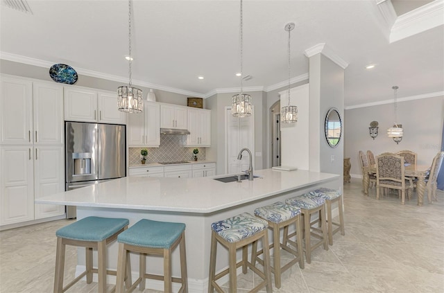 kitchen with white cabinetry, stainless steel fridge, sink, and pendant lighting