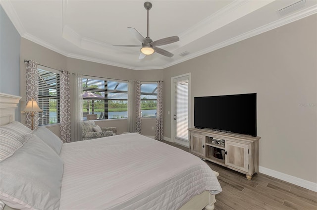 bedroom with a tray ceiling, ornamental molding, access to outside, ceiling fan, and light hardwood / wood-style floors