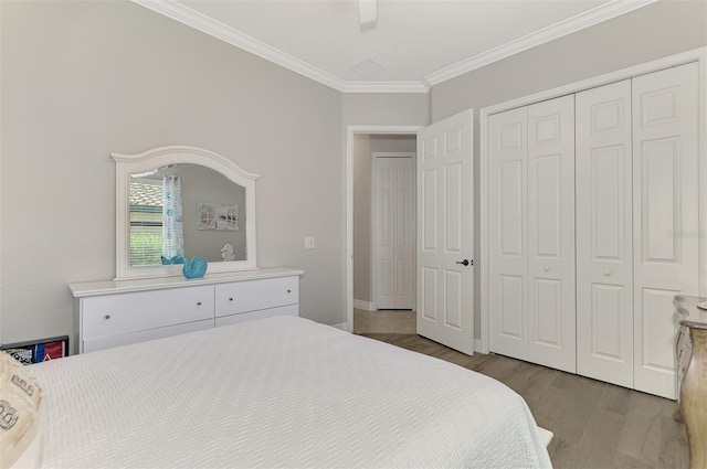 bedroom with crown molding, hardwood / wood-style floors, ceiling fan, and a closet