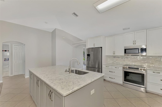 kitchen featuring arched walkways, visible vents, backsplash, appliances with stainless steel finishes, and a sink