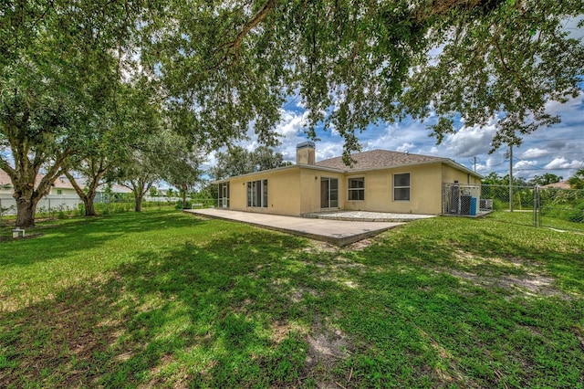 rear view of house with fence private yard, a chimney, a lawn, and stucco siding