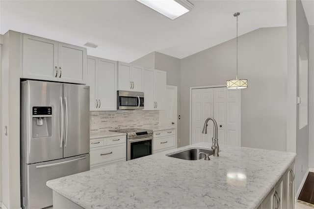 kitchen featuring pendant lighting, stainless steel appliances, sink, and a center island with sink