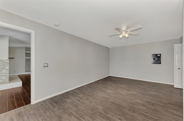 unfurnished room featuring dark wood-type flooring, a fireplace, and ceiling fan