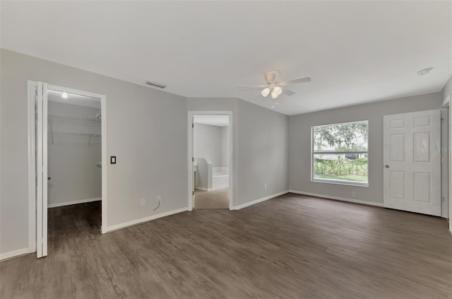 unfurnished bedroom with ceiling fan, ensuite bathroom, dark hardwood / wood-style flooring, a spacious closet, and a closet