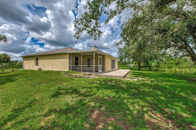 rear view of house with a patio, a sunroom, and a yard