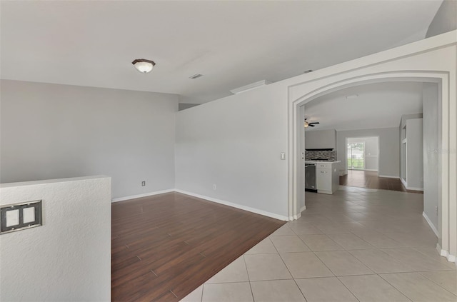 unfurnished room with arched walkways, baseboards, visible vents, and light wood-style floors