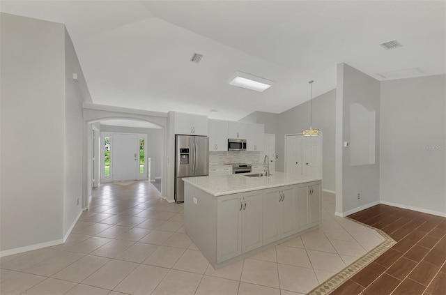 kitchen with arched walkways, visible vents, stainless steel appliances, and a sink