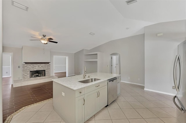 kitchen featuring light tile patterned floors, a sink, a ceiling fan, appliances with stainless steel finishes, and a tiled fireplace