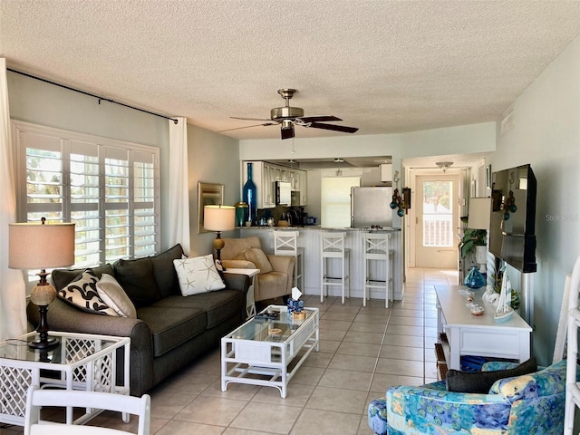 tiled living room featuring ceiling fan and a textured ceiling