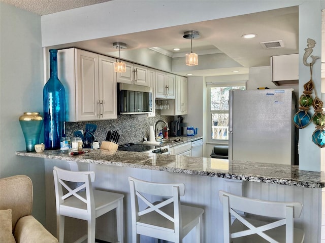 kitchen featuring fridge, white cabinetry, decorative light fixtures, and sink