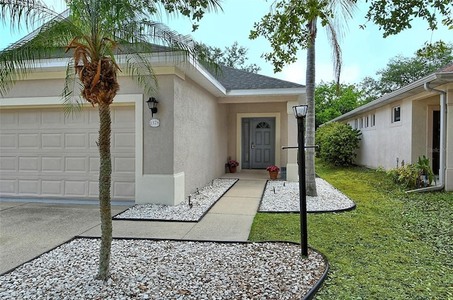 view of exterior entry with a garage and a yard