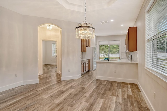 kitchen with pendant lighting, tasteful backsplash, white fridge, kitchen peninsula, and light wood-type flooring