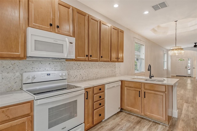 kitchen featuring sink, light wood-type flooring, pendant lighting, white appliances, and decorative backsplash