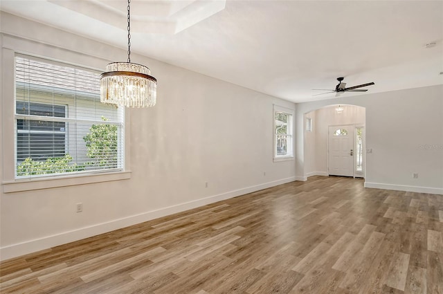 unfurnished living room featuring hardwood / wood-style flooring and ceiling fan with notable chandelier