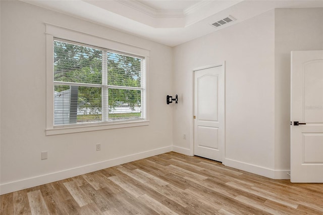 unfurnished room with ornamental molding, light hardwood / wood-style floors, and a raised ceiling