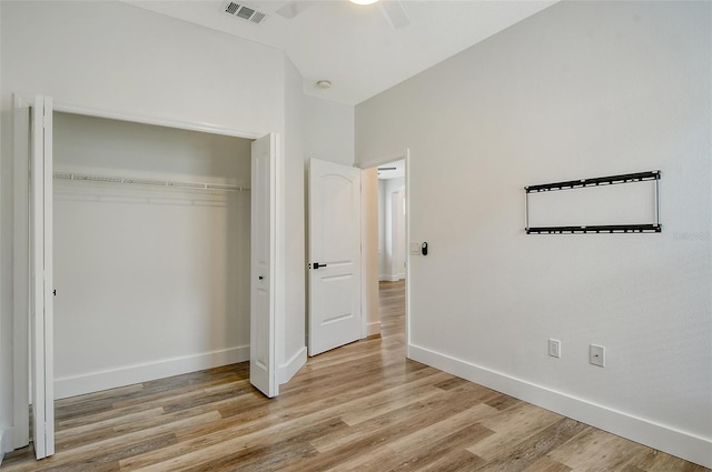 unfurnished bedroom with light wood-type flooring, ceiling fan, and a closet