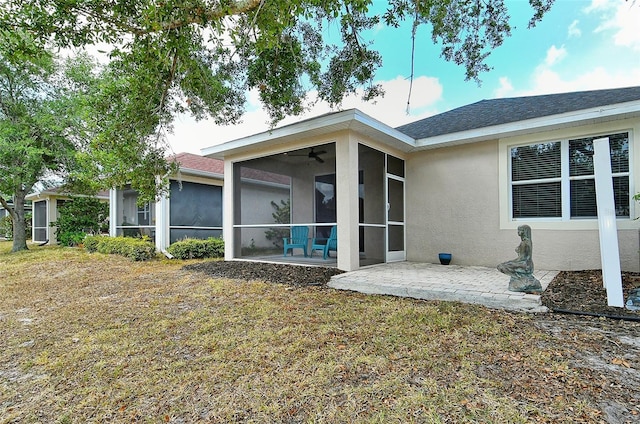 back of house featuring ceiling fan, a sunroom, a patio area, and a lawn