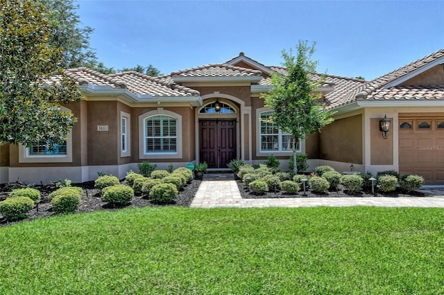 mediterranean / spanish house with a garage and a front yard