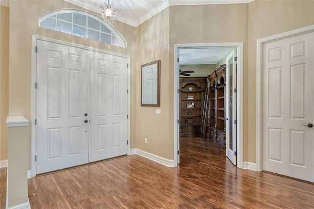 entryway with ornamental molding, dark hardwood / wood-style floors, and an inviting chandelier