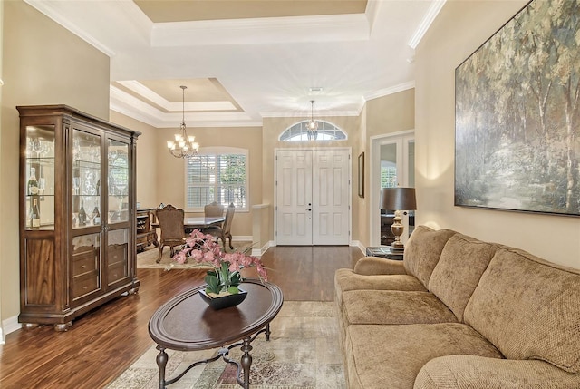 living room featuring crown molding, a tray ceiling, dark hardwood / wood-style floors, and an inviting chandelier