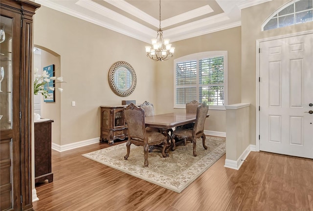 dining room with ornamental molding, a tray ceiling, hardwood / wood-style floors, and a notable chandelier