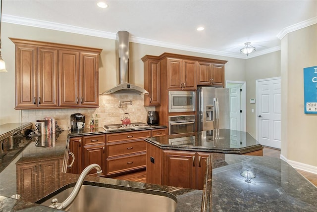 kitchen featuring wall chimney range hood, sink, dark stone countertops, stainless steel appliances, and a kitchen island