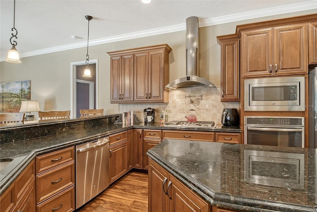 kitchen with hanging light fixtures, appliances with stainless steel finishes, decorative backsplash, and wall chimney exhaust hood