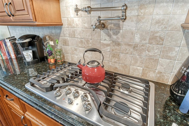 kitchen with dark stone countertops, decorative backsplash, and stainless steel gas cooktop