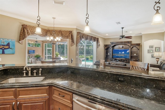 kitchen featuring sink, dark stone countertops, ornamental molding, pendant lighting, and ceiling fan with notable chandelier