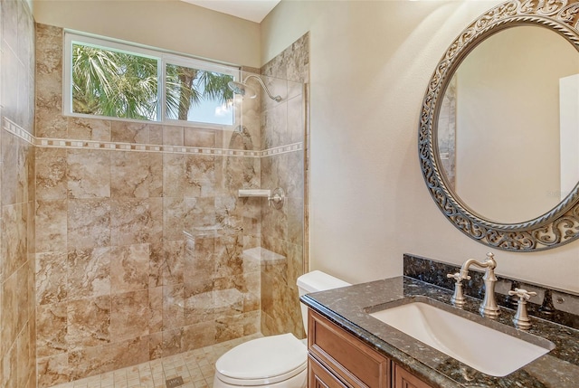 bathroom with vanity, toilet, and a tile shower