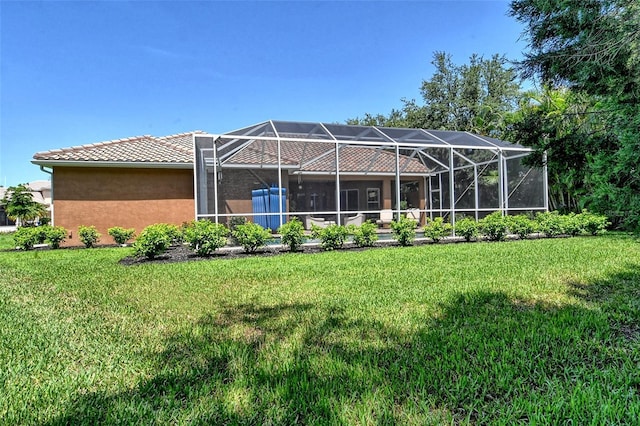 rear view of house featuring a yard and glass enclosure