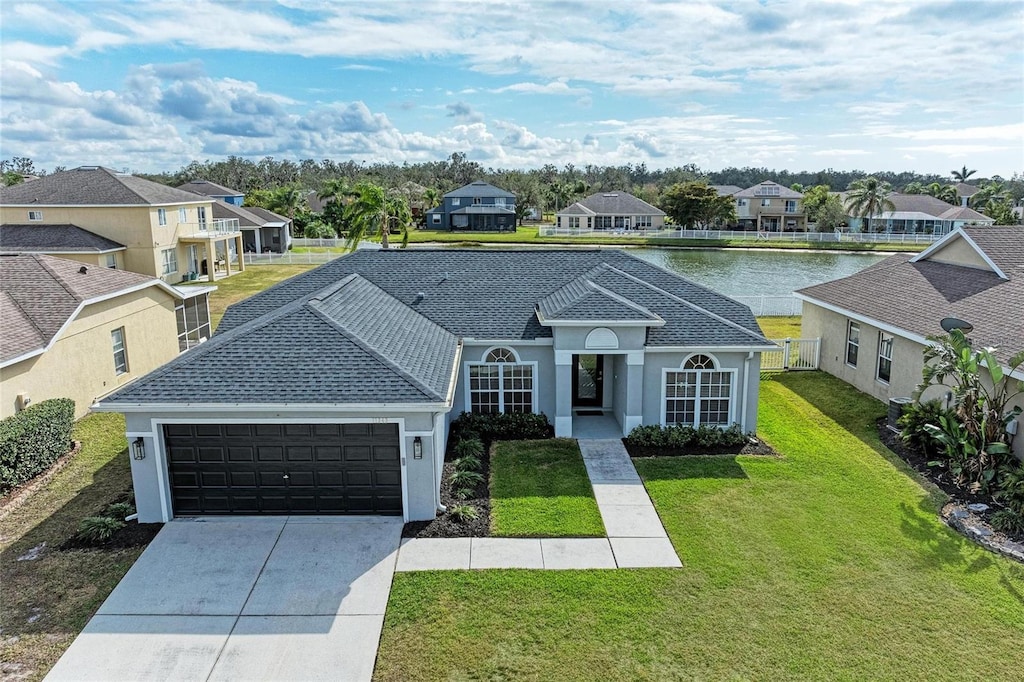 view of front of home featuring a garage, a front lawn, and a water view