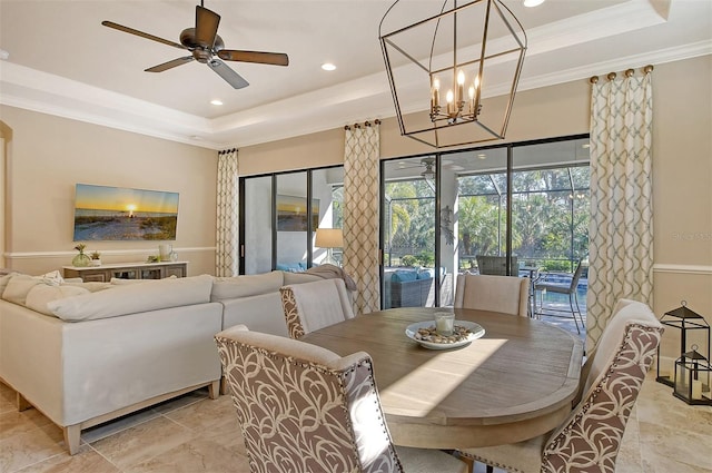 dining area with ornamental molding, ceiling fan with notable chandelier, and a tray ceiling