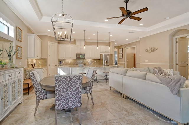 dining room featuring crown molding, a tray ceiling, and ceiling fan with notable chandelier