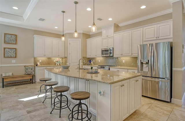 kitchen with white cabinetry, appliances with stainless steel finishes, light stone counters, and a center island with sink