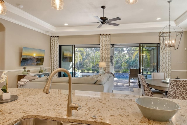 kitchen with sink, crown molding, ceiling fan, light stone countertops, and a raised ceiling