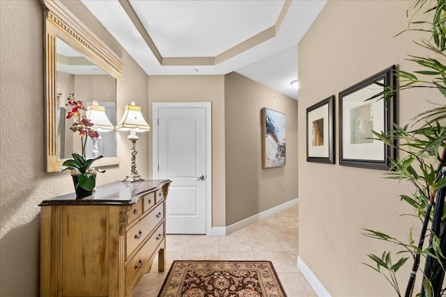 hallway with light tile patterned flooring and a raised ceiling