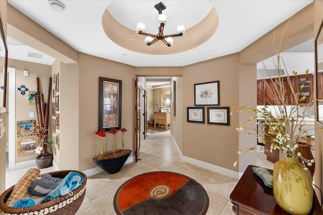 hallway featuring light tile patterned floors, a chandelier, and a tray ceiling